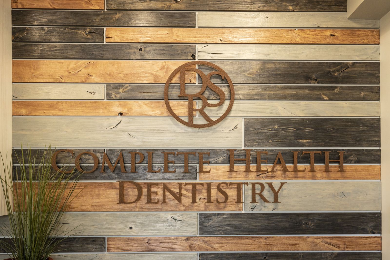 DSR monogram and Complete Health Dentistry lettering on a reclaimed-wood wall